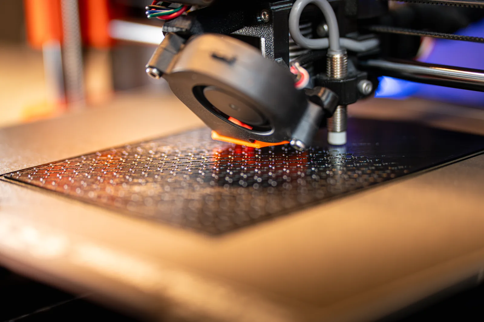 Impresora FDM imprimiendo un prototipo, con la primera capa fundida sobre la base